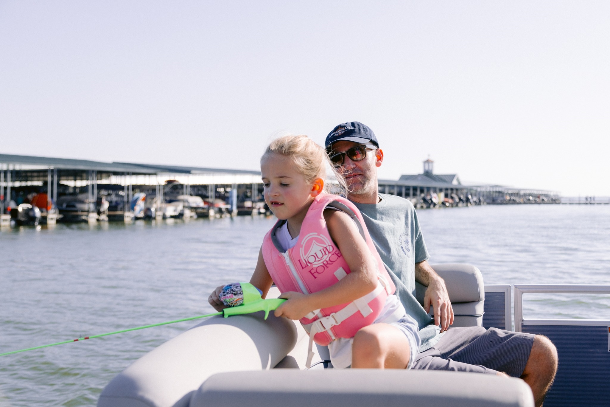 A little girl fishing over the side of a boat