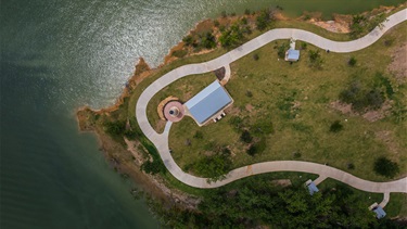 Drone shot of grass and the lake with a pavilion in the middle