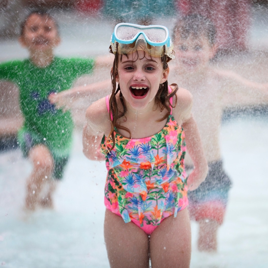 Girl laughing as water dumps on her from an attraction at the cove