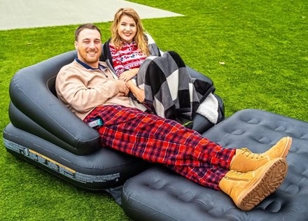 A man and woman lounging on an inflatable chair 