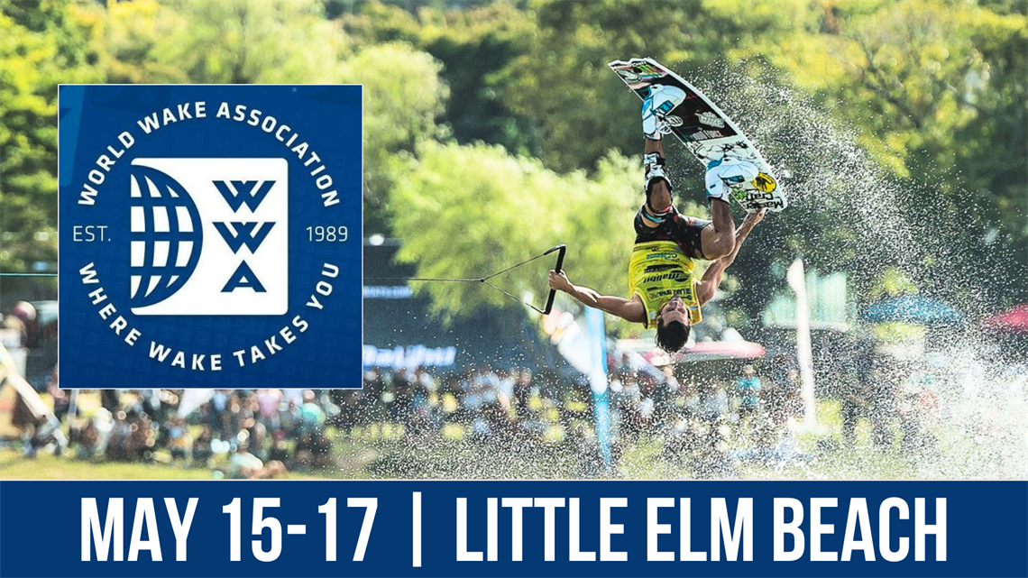 A person performs an aerial wakeboarding trick on a sunny day, near an event sign for the World Wake Association. The sign features the WWA logo and the text 